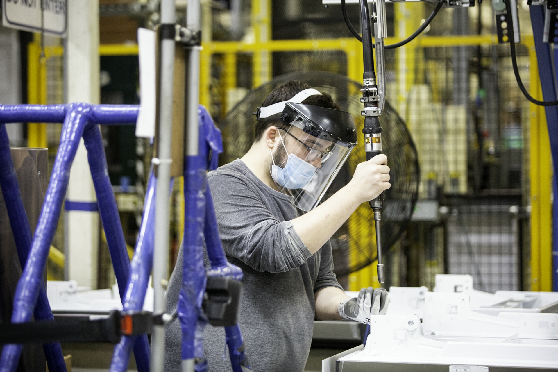 A GE Appliances employee wearing advanced personal protective equipment works the assembly line.
