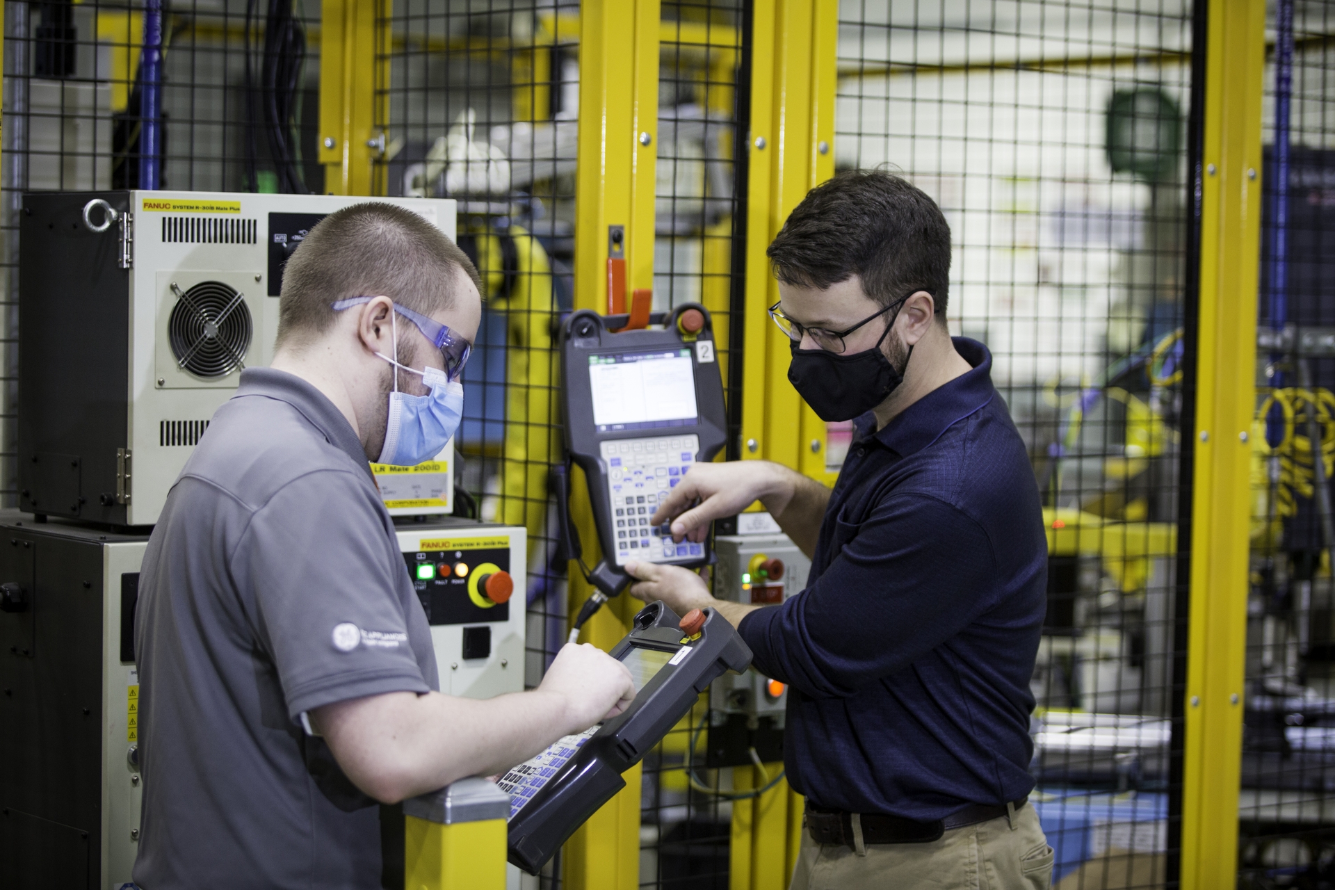 Two employees on GE Appliances’ Industry 4.0 Development Program – Jordan Klotz (left) and Collie Crawford (right) – discuss short cuts for “pick and place” routines on the robot teach pendant for the new automated dishwasher spray arm assembly cell.