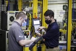 Two employees on GE Appliances’ Industry 4.0 Development Program – Jordan Klotz (left) and Collie Crawford (right) – discuss short cuts for “pick and place” routines on the robot teach pendant for the new automated dishwasher spray arm assembly cell.