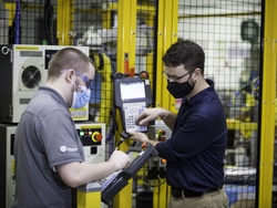 Two employees on GE Appliances’ Industry 4.0 Development Program – Jordan Klotz (left) and Collie Crawford (right) – discuss short cuts for “pick and place” routines on the robot teach pendant for the new automated dishwasher spray arm assembly cell.