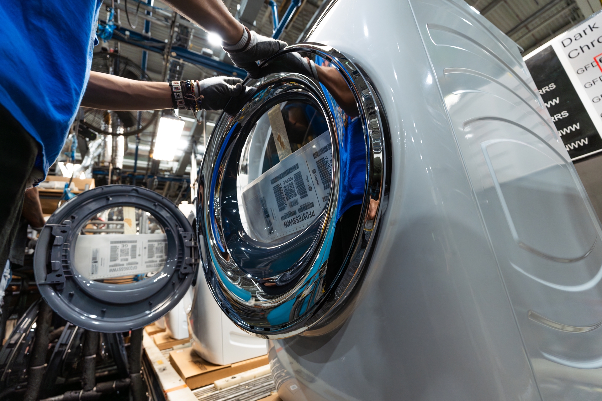A chrome-plated trim ring from Wabash Plastics in Indiana is fitted onto a front-load dryer door. This U.S.-made component will also be used on the new laundry line launching at Appliance Park.