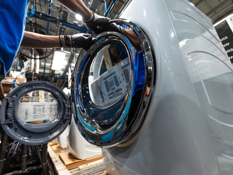 A chrome-plated trim ring from Wabash Plastics in Indiana is fitted onto a front-load dryer door. This U.S.-made component will also be used on the new laundry line launching at Appliance Park.