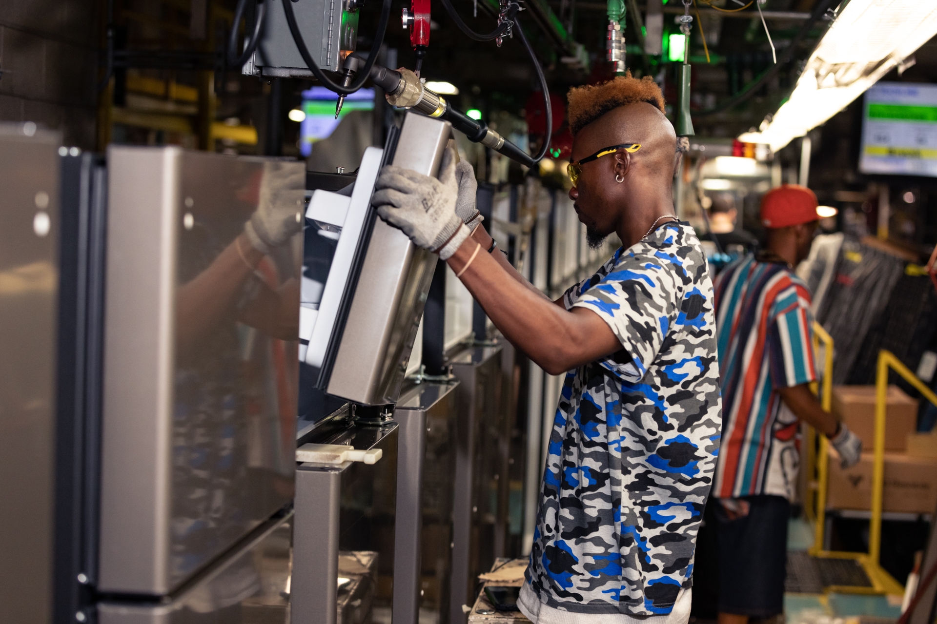 A team member at the GE Appliances Decatur AL plant installs components on a top freezer refrigerator.