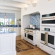  CAFÉ's Matte White appliances outfitted with Brushed Brass hardware stand out against the bold blue quartzite countertops and backsplash 