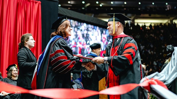 UNM President Garnett Stokes congratulates graduate.