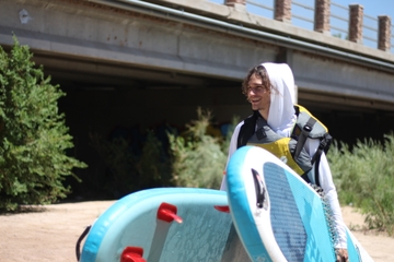 Paddleboarder carries paddleboard
