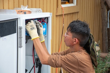 A student works on the wiring of the solar panel’s system inverter.