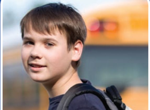 boy with backpack in front of school bus