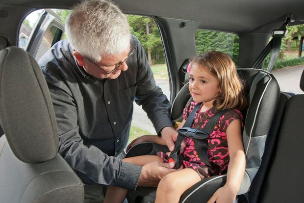 Grandpa fastens child in booster seat