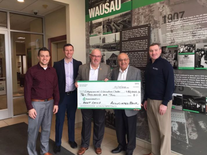 Associated Bank colleagues (from left to right) Jordan Hoerter, Chad Otte, Alfred Nakhla and Andy Shallow, present a check to Romey Wagner (center).