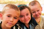 three carseat age kids smile at camera