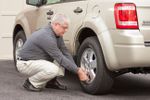Senior driver checking tire pressure