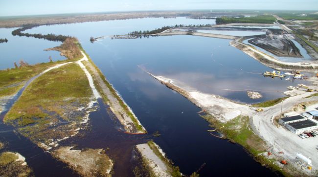 Sutton discharge canal flows past submerged steel wall retaining ash in the 1971 ash basin before entering Sutton cooling lake; 1984 ash basin (upper right) remains unaffected. Photo uploaded on Sept. 22, 2018.