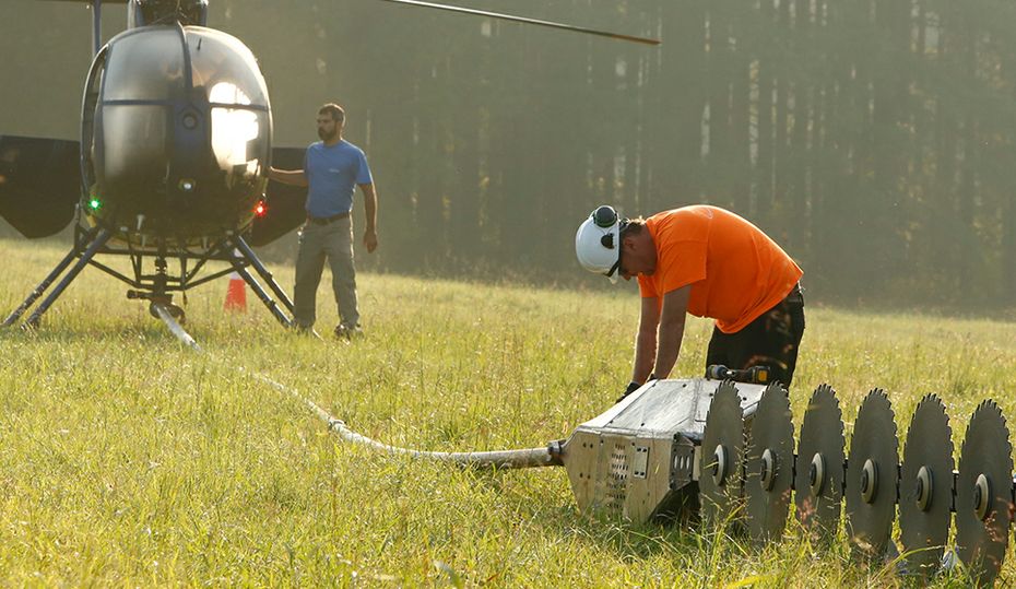 Helicopter with saw trims trees from the sky