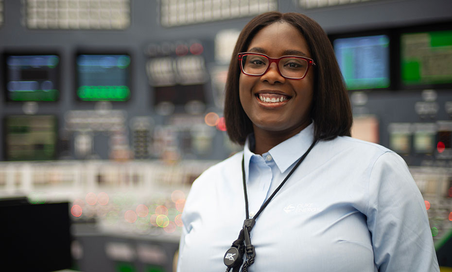 Amanda Shepard, a Black woman with short brown hair, wears a pair of glasses and smiles for a picture at a Duke Energy power plant.