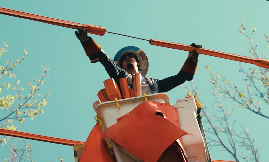 A lineworker in a bucket truck applying protective cover up on a power line.