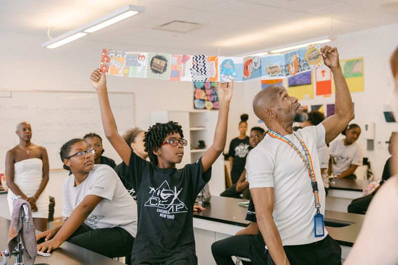 AileyCamp New York Director Damazi Williams with participants showcasing artwork in Creative Communications class