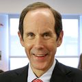 Brian Druker, M.D., a tall man with thin dark hair smiling in a suit.