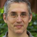 man with gray hair, glasses, smiling at camera