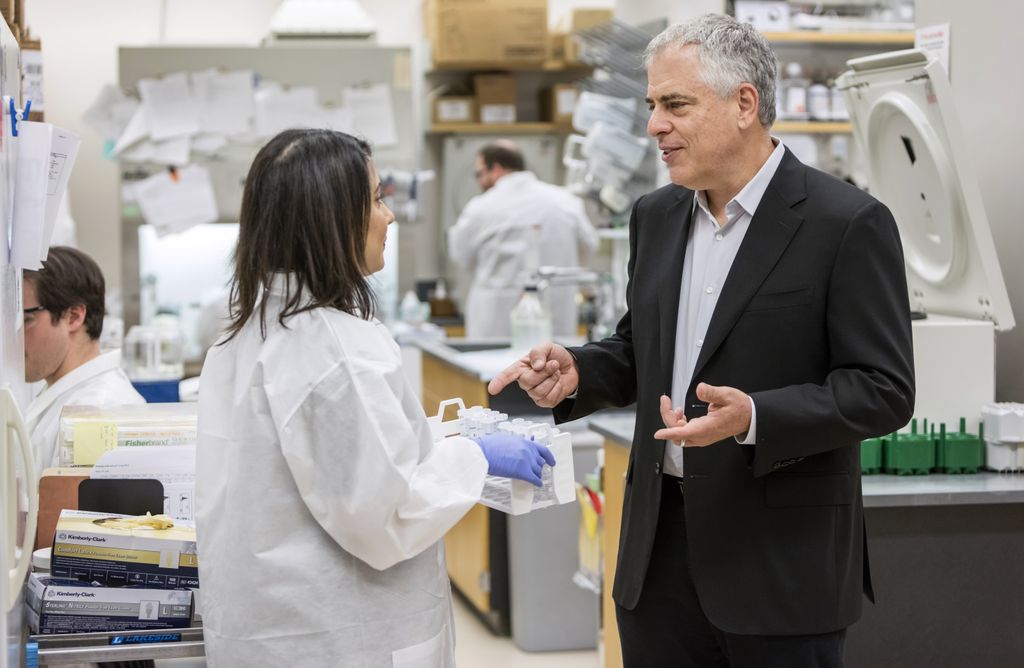 researcher in suit, dr. picker on right, talks with a scientist in the laboratory