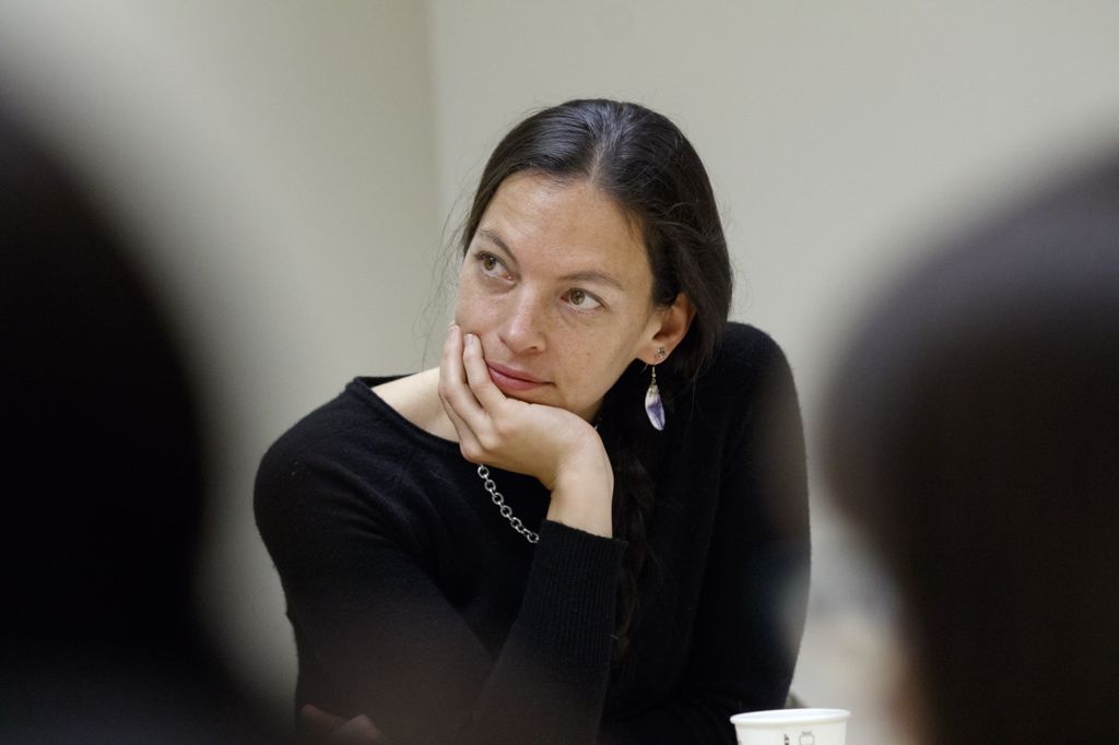 woman resting her chin on her hand and listening to a speaker