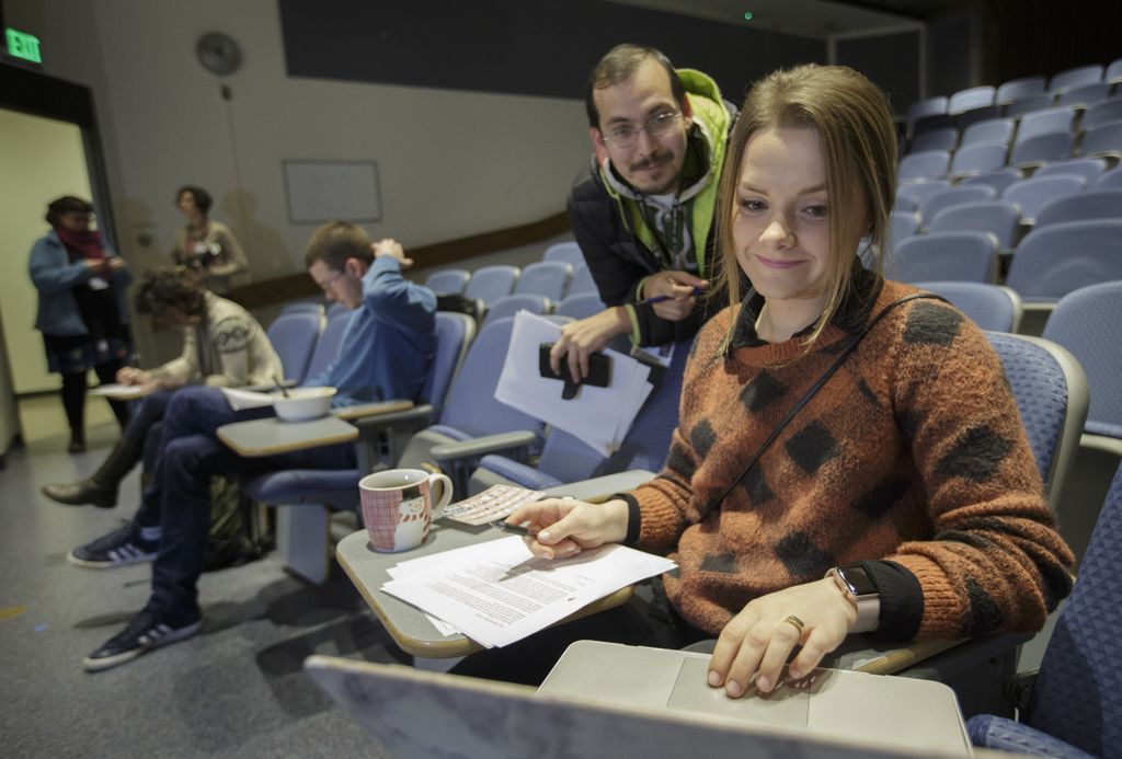 two students looking at computer while they write letters