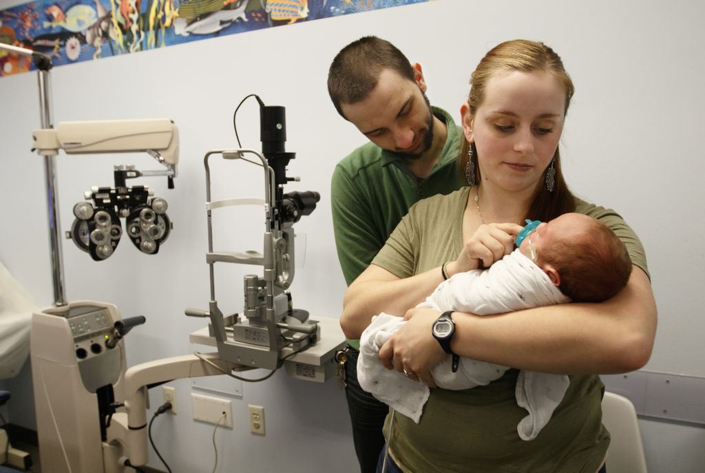 young couple at the eye doctor with their infant