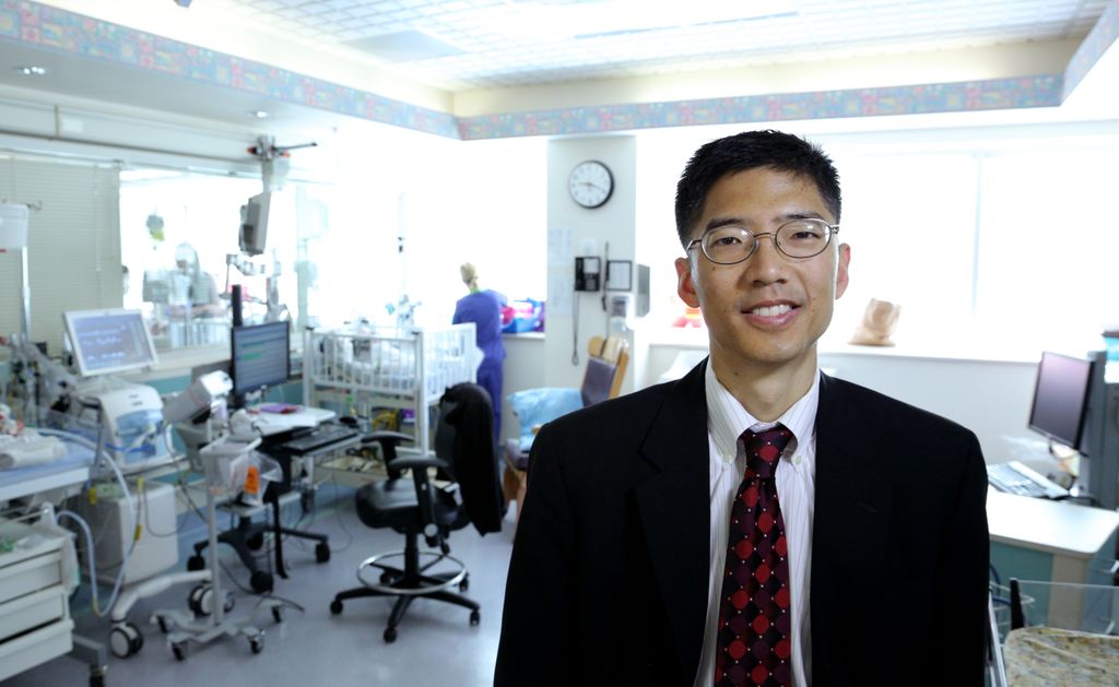 man in suit smiling in a camera while standing in a lab