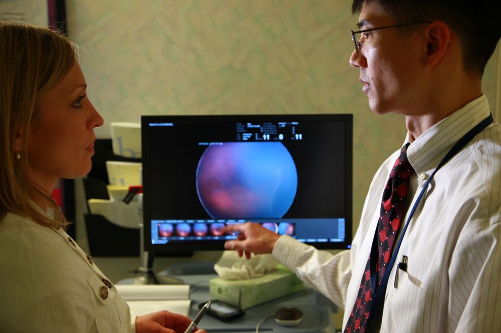screen showing the image of an eye, with two doctors in front in discussion