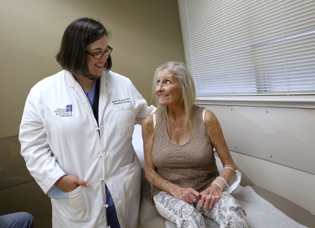 Liver donation recipient looks up at her transplant doctor, smiling