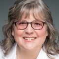 Sancy Leachman, M.D., Ph.D., in a white coat and gray background.