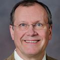 headshot of man, with glasses, looking at camera