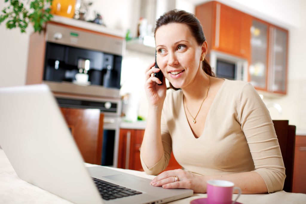 woman at desk in front of a computer, talking on a phone