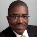 African-american man, wearing glasses, with a light moustache, wearing coat and tie, looking at camera
