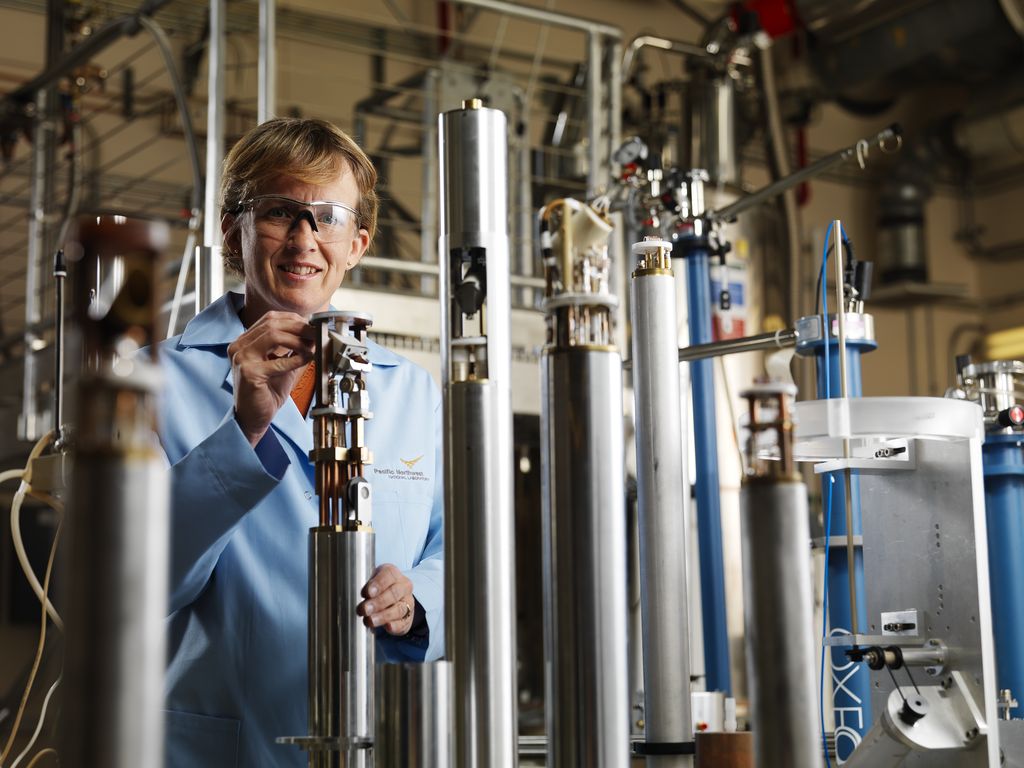 female scientist standing behind a row of research machines