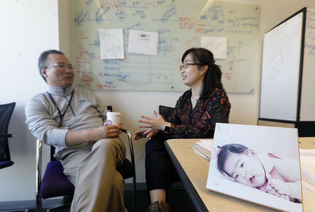 husband and wife meeting in an office, a photo of their daughter is on the desk, at the right.