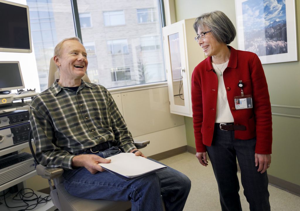 man sitting in chair, laughing with his doctor