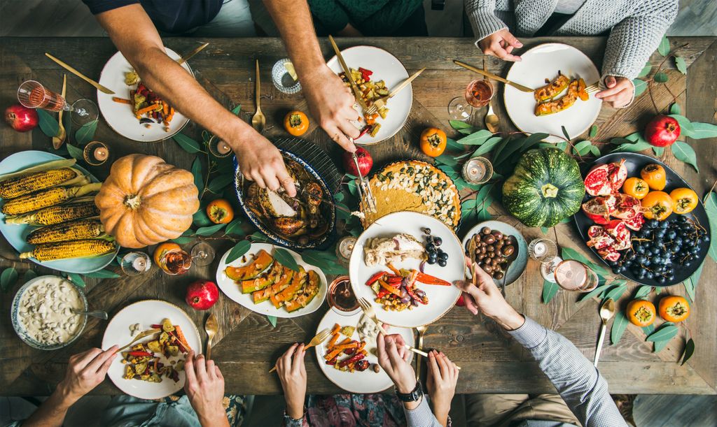 overhead shot of a table filled with holiday entrees, and people passing their plates