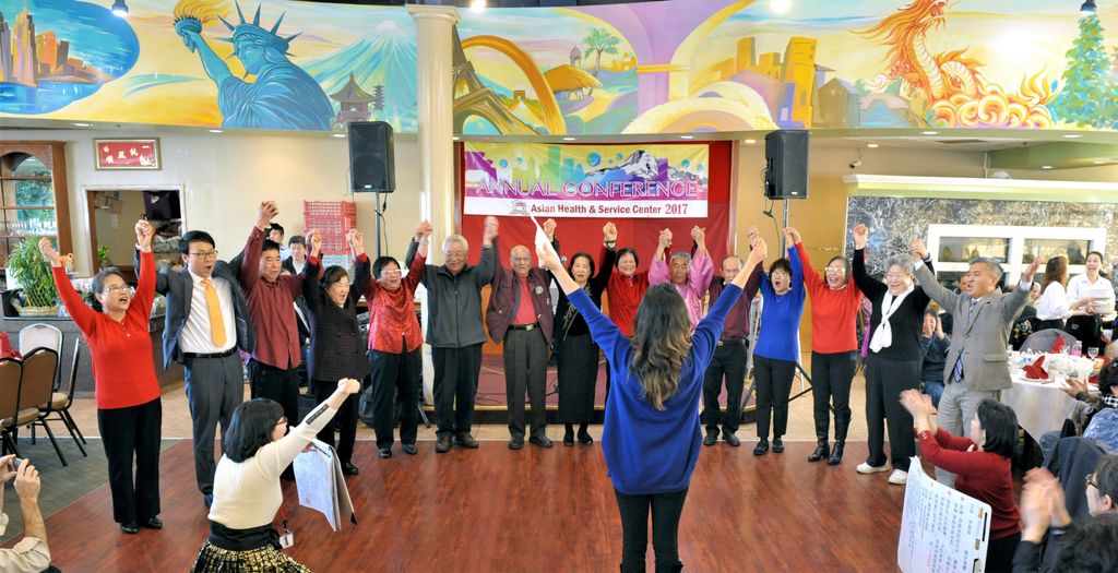 large group of people standing together hand in hand with arms raised above heads