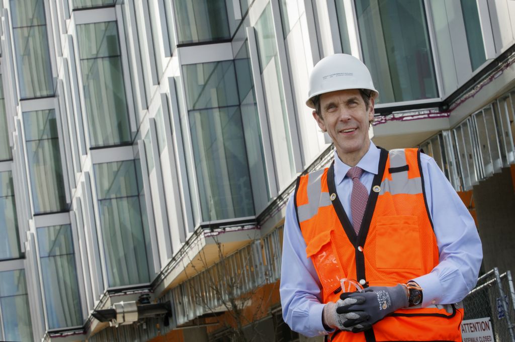 man in orange vest and hard hat standing in front of a building under construction