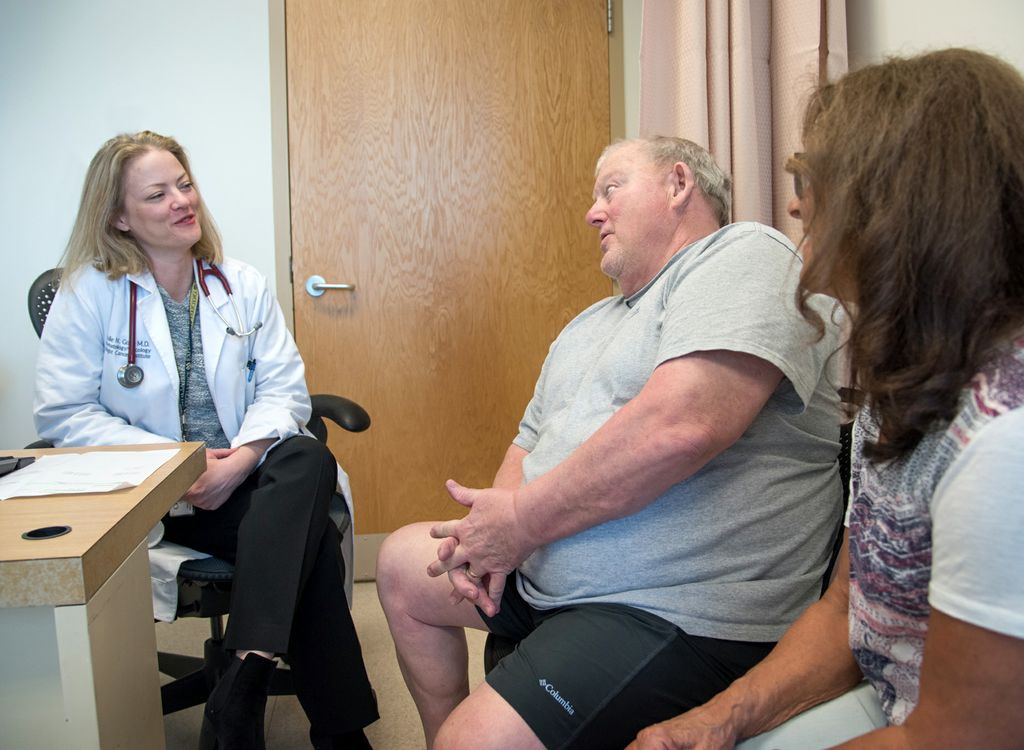 doctor on left, meeting with patient and his wife in a medical appointment