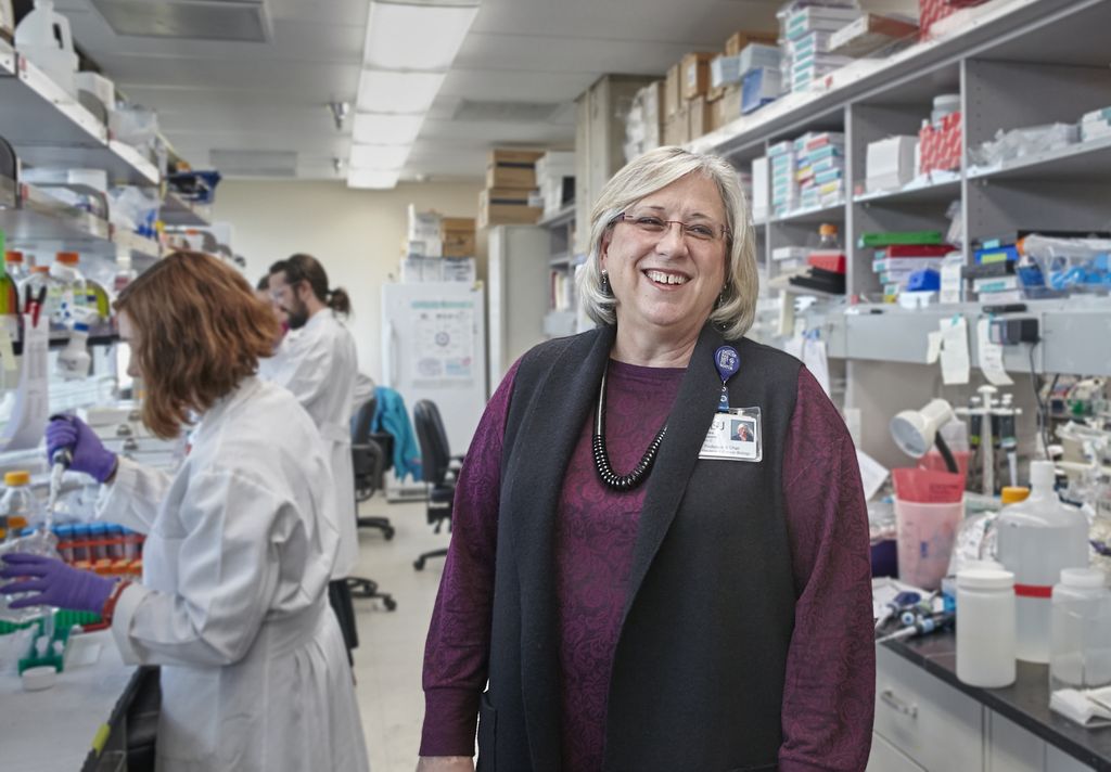 woman standing in a laboratory, looking at camera and smiling