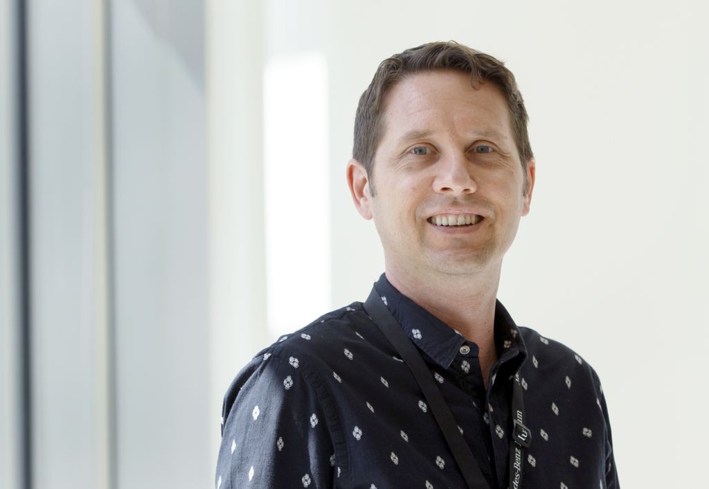 man wearing dark shirt smiling at camera