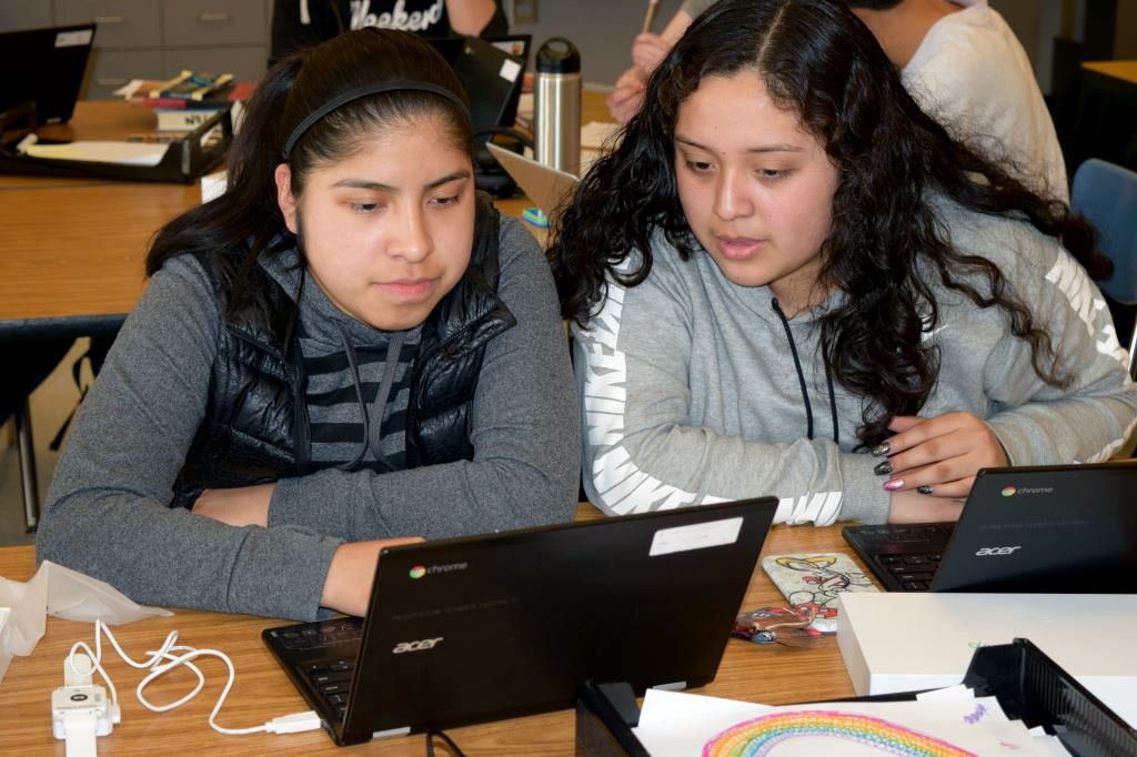 two teenage girls, working together on a computer
