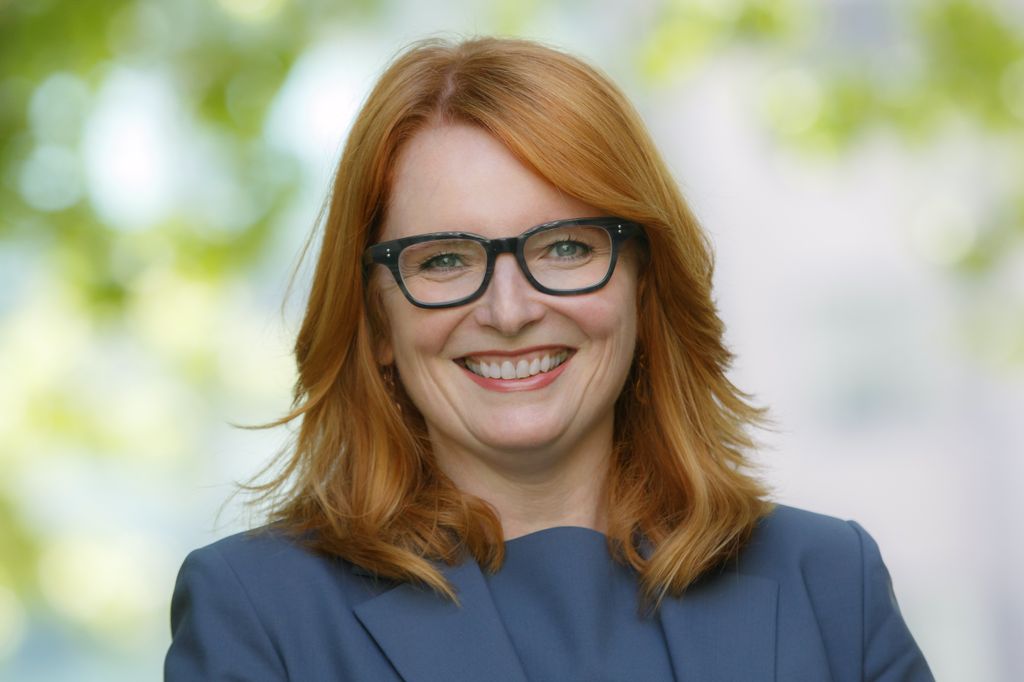 Headshot of Connie Seeley, a smiling, red-haired caucasian woman wearing glasses and a green top