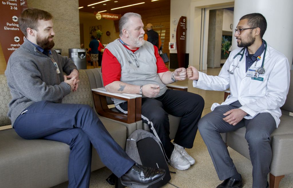three men visiting on a couch in the lobby of the hospital