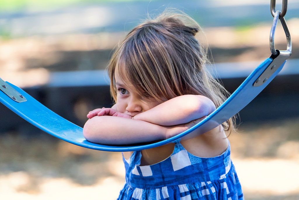 sad girl leaning on a swing