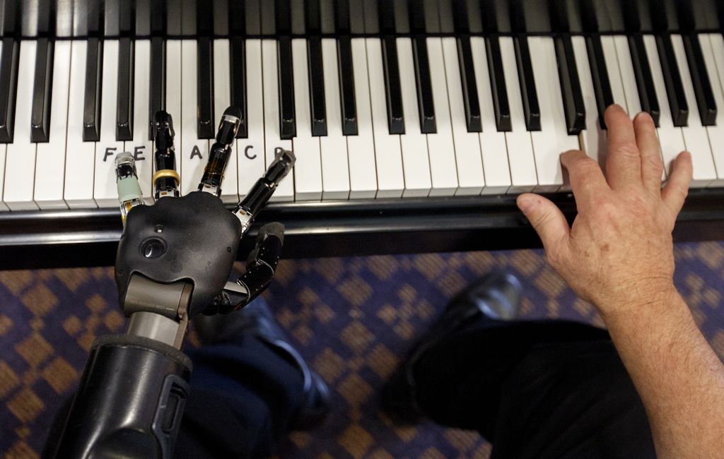 two hands on a piano keyboard, left hand is robotic