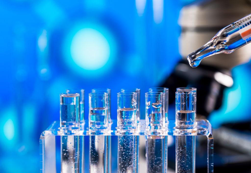 detail photo of a row of a dropper adding liquid to a row of test tubes