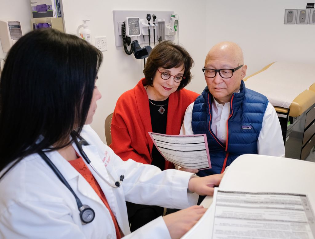 Three people, two woman on left, and a man on the right, looking at paperwork